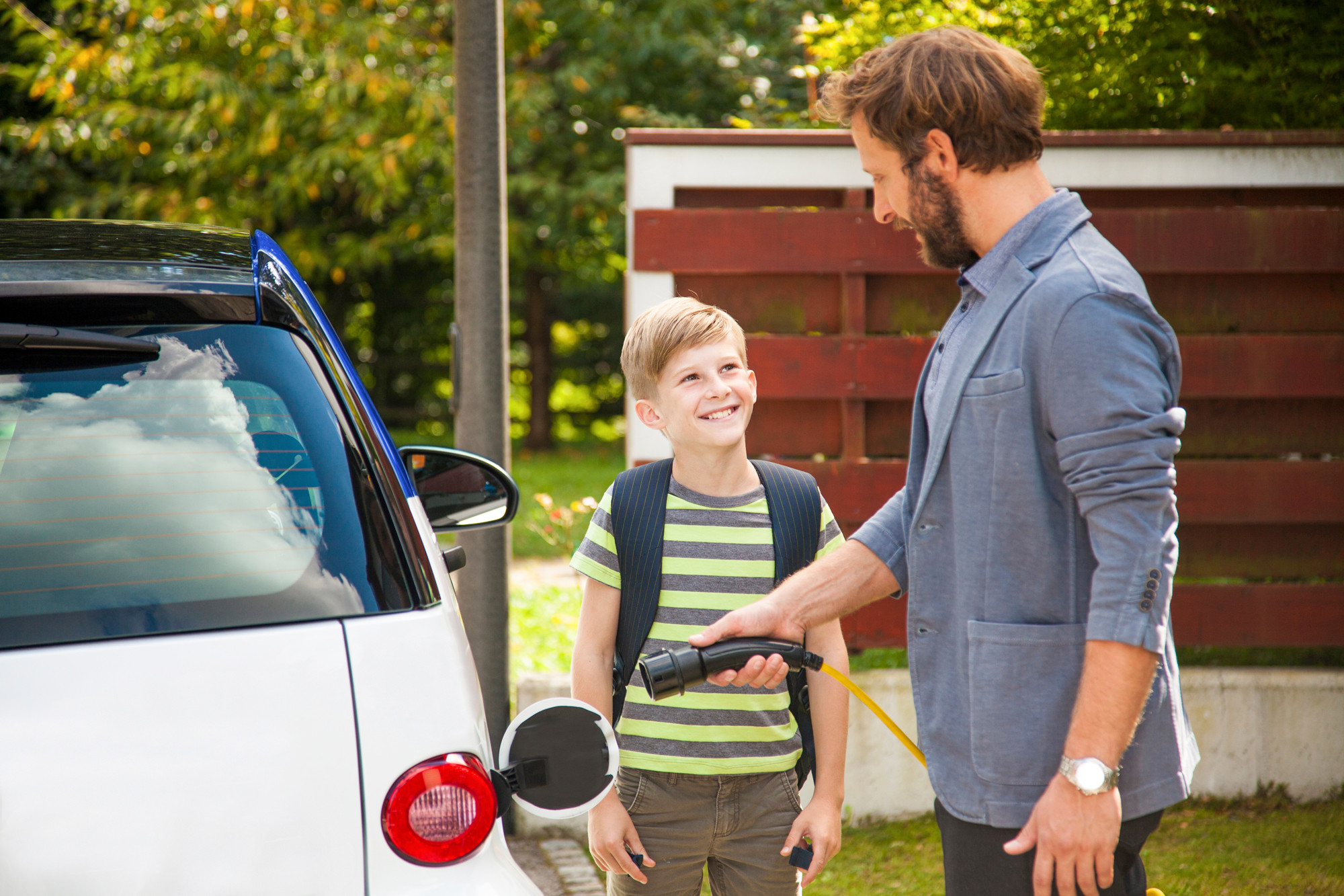 Vater und Sohn beim Betanken eines Elektroautos.