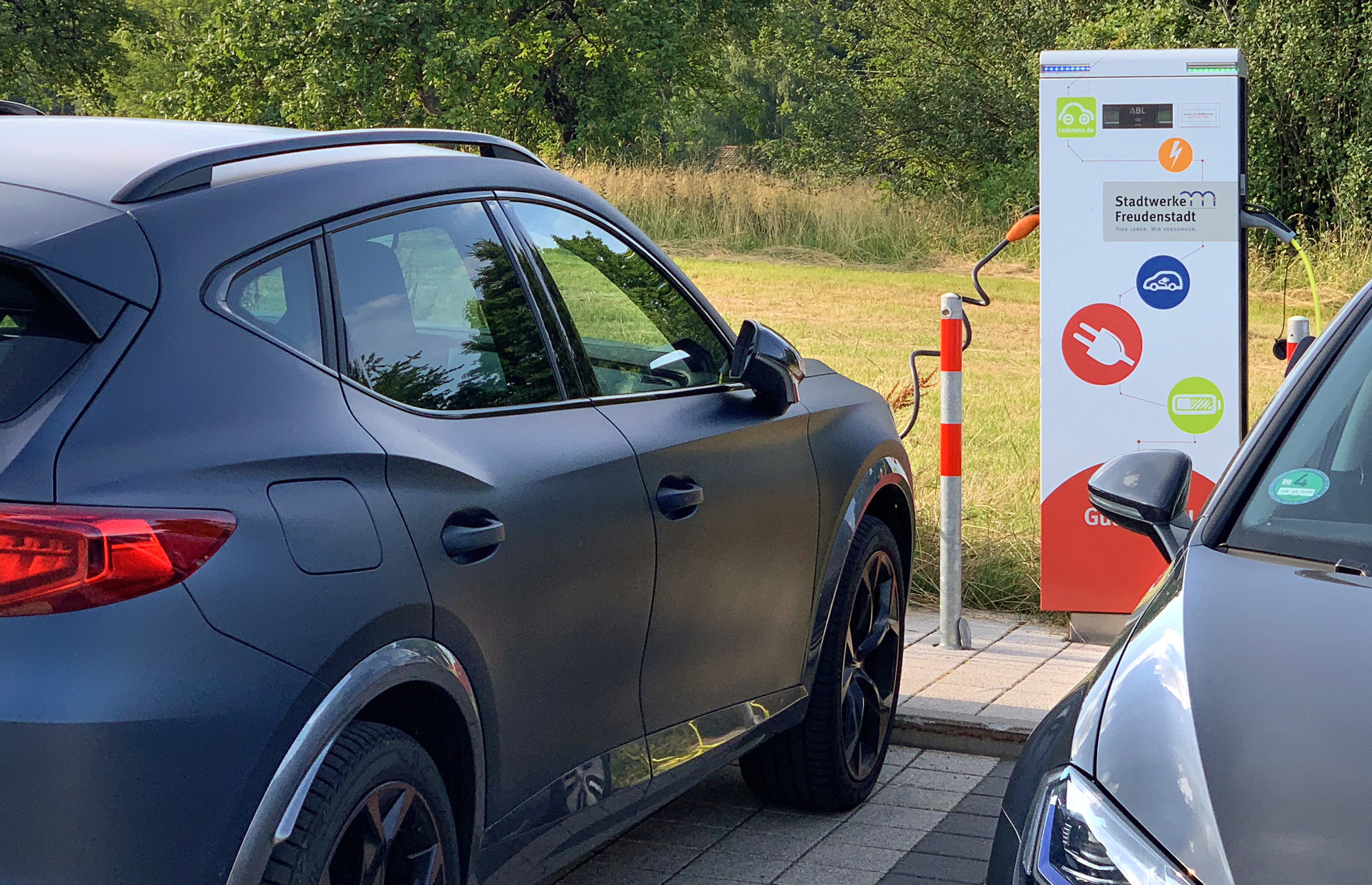 Elektrofahrzeug beim Ladevorgang an einer E-Lades&auml;ule.